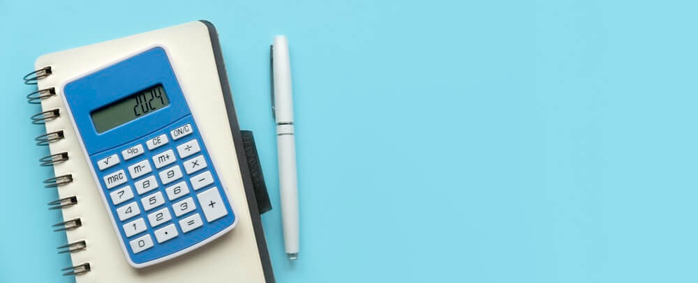 Calculator and notepad with pen on a blue background.