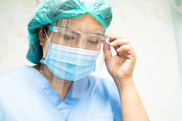 Nurse wearing personal protective equipment, including a face mask and face shield.