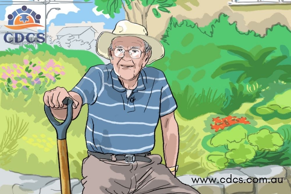 Elderly caucasian man sitting in his garden holding the handle of a gardening tool.